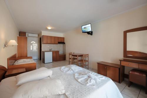 a room with two beds and a television and a kitchen at Paradise Hotel Apartments Sidari in Sidari