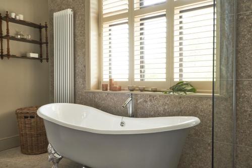 a white bath tub in a bathroom with a window at The Lakes By YOO in Lechlade