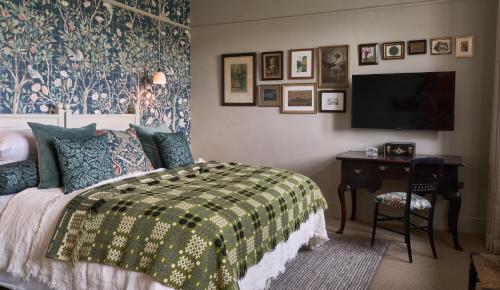 a bedroom with a bed and a desk with a television at The Lakes By YOO in Lechlade