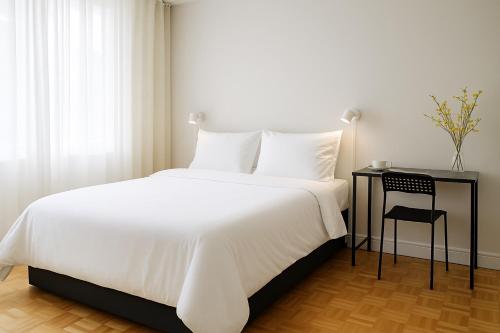 a bedroom with a white bed and a table with a chair at Private Deluxe Room in Downtown Toronto, Steps to Subway & CN Tower in Toronto