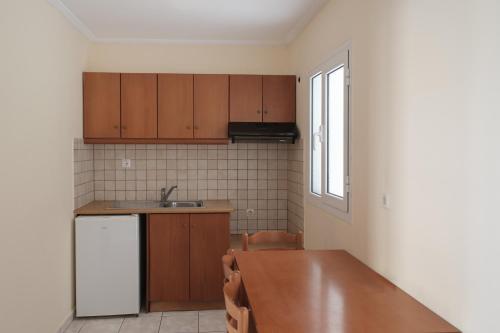 a kitchen with wooden cabinets and a wooden table at Paradise Hotel Apartments Sidari in Sidari