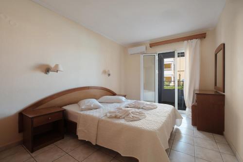 a bedroom with a bed with towels on it at Paradise Hotel Apartments Sidari in Sidari