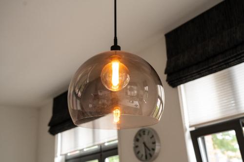 a glass pendant light hanging in a room with a clock at Quiet and cosy apartment near the city center of Diest in Diest