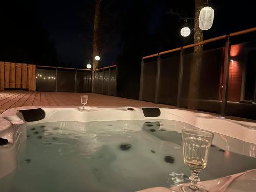 a bath tub with a glass of wine in it at Log cabin with hot tub and views in Ludvigsborg