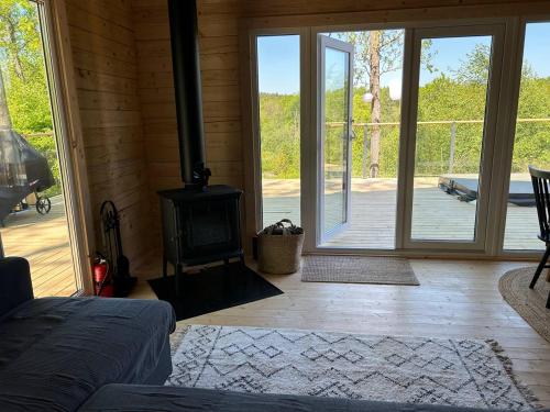 a living room with a woodburning stove and a patio at Log cabin with hot tub and views in Ludvigsborg