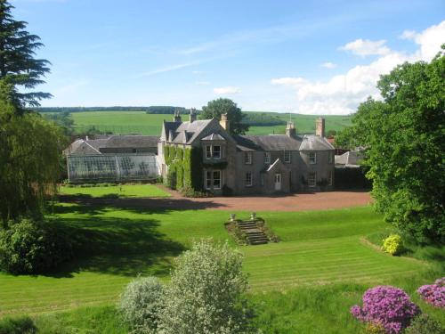 an old house in the middle of a green field at Newton Farmhouse B & B in Jedburgh