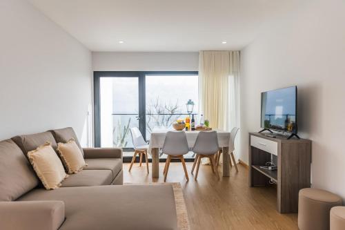 a living room with a couch and a table with a television at Fonte Da Rocha - OCEAN VIEW in Ponta Delgada