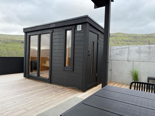 a black tiny house on a deck with a table at Leynastova - Luxurious & Unique Villa in Leynar
