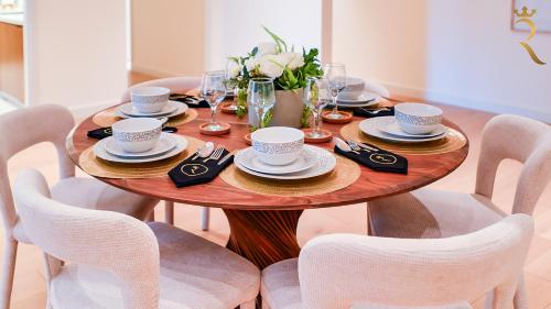 a wooden table with cups and saucers on it at Modern 3BR - Chic Coastal Escape in Abu Dhabi