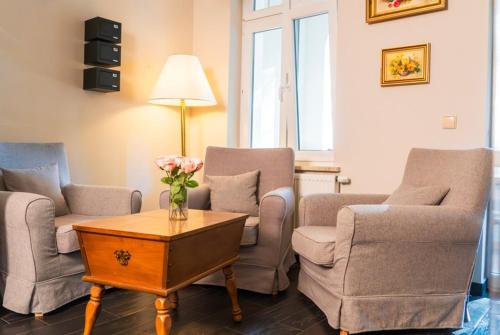 a living room with chairs and a table with a vase of flowers at Villa Lessing in Polanica-Zdrój