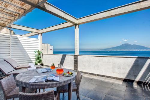 a table and chairs on a patio with a view of the ocean at Towers Hotel Stabiae Sorrento Coast in Castellammare di Stabia