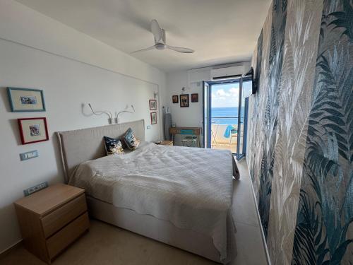 a white bedroom with a bed and a balcony at Big Blue New in Agios Nikolaos