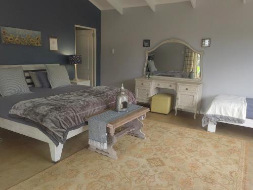 a bedroom with a bed and a table and a mirror at Sounds in Silence - Misty Forest Garden in Balgowan