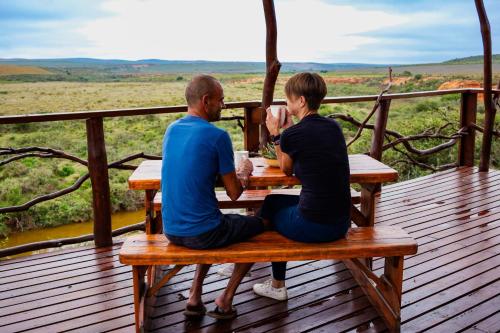 a man and woman sitting at a picnic table on a deck at Canyon Cottage in Cloeteskraal
