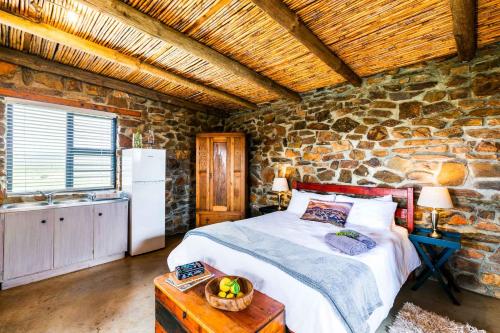 a bedroom with a bed and a stone wall at Canyon Cottage in Cloeteskraal