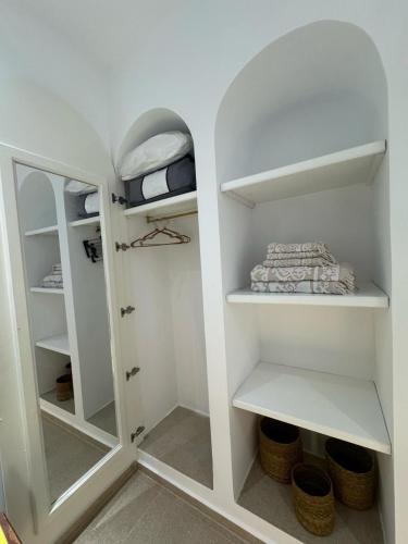 a walk in closet with white shelves and a mirror at Dar Rmila à Mahdia, Borj Errass in Mahdia