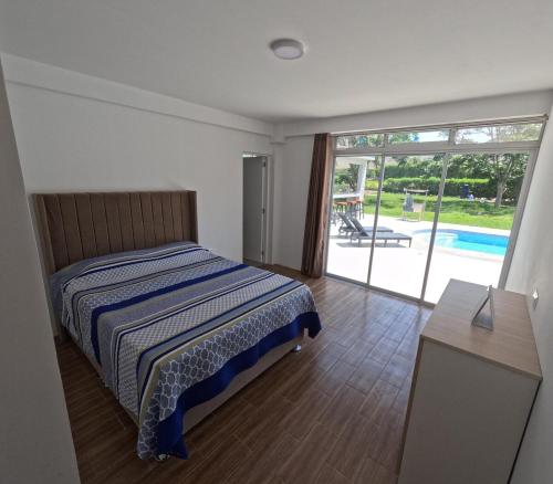 ein Schlafzimmer mit einem Bett und Blick auf einen Pool in der Unterkunft Casa campo las Pecanas Huaral 