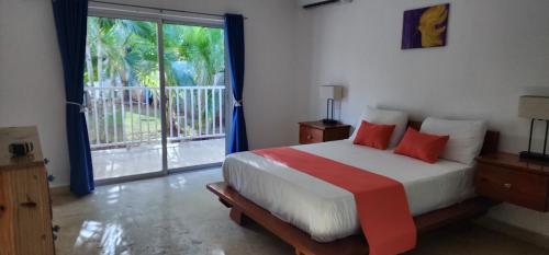 a bedroom with a bed with red pillows and a window at Room for 2 w kitchen pool close to the beach in Las Galeras