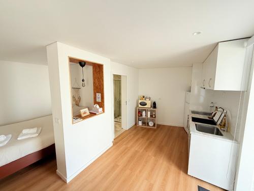 a kitchen with white cabinets and a wooden floor at Casinha no caminho de Santiago in Belinho