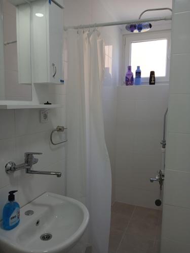 a bathroom with a white shower curtain and a sink at Apartman Dijana in Subotica