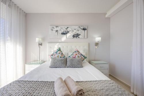 a white bedroom with a large white bed with pillows at Luxury Beachfront Apartment in Blouberg- 1 bedroom in Bloubergstrand