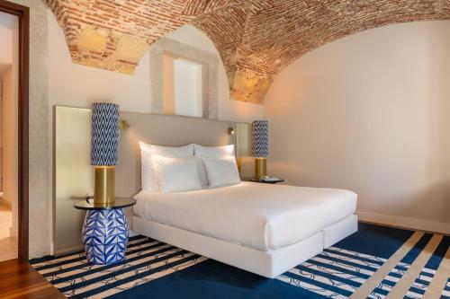 a bedroom with a white bed and a blue rug at Palácio do Governador - Lisbon Hotel & Spa in Lisbon