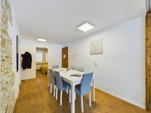 a dining room with a white table and blue chairs at Alpine magic for the whole family near Zermatt with parking! in Täsch