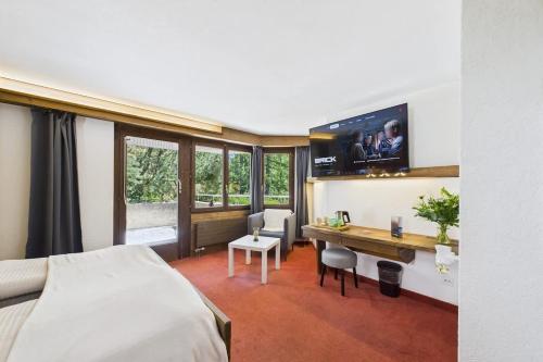a hotel room with a bed and a desk with a tv at Charming Little Getaway in the Heart of Saas-Fee in Saas-Fee