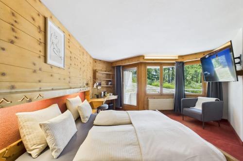 a bedroom with a large bed and a tv at Easystay Modernes Budget-Zimmer im Zentrum von Saas-Fee in Saas-Fee