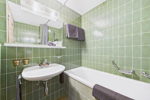 a green tiled bathroom with a sink and a tub at Charming Little Getaway in the Heart of Saas-Fee in Saas-Fee