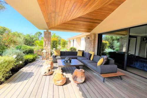 a patio with a couch and tables on a wooden deck at Villa Pignotulli Di Cirendinu in Sainte-Lucie de Porto-Vecchio