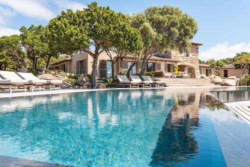 una piscina con sedie a sdraio di fronte a una casa di Casa Rocca Di Pianotolli a Pianottoli-Caldarello