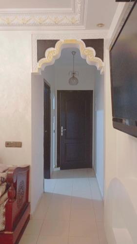 a hallway with a black door and a tv at Riyad maison in Ifrane