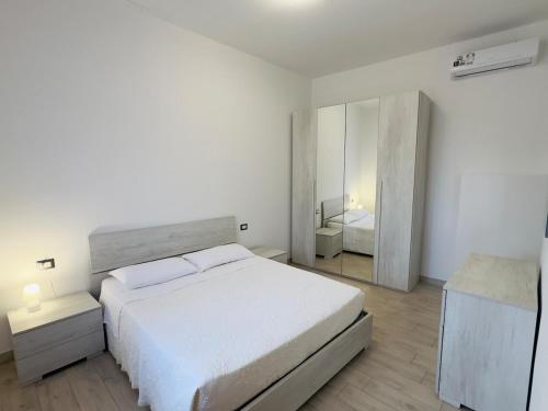 a white bedroom with a large bed and a mirror at Era apartments 2 in Caponago