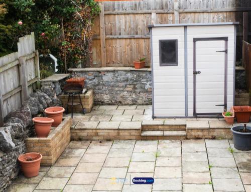a small white shed in a garden with potted plants at Barry Vibes 3BR House by The One Retreats Short Lets & Serviced Accommodation Barry close to Barry Island in Biglis