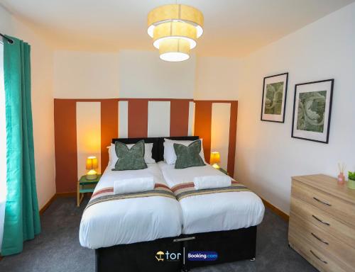 a bedroom with a large bed with a wooden headboard at Barry Vibes 3BR House by The One Retreats Short Lets & Serviced Accommodation Barry close to Barry Island in Biglis