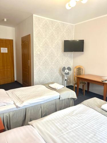 a room with three beds and a table and a tv at Hotel i Restauracja Borowianka in Ostrów Wielkopolski