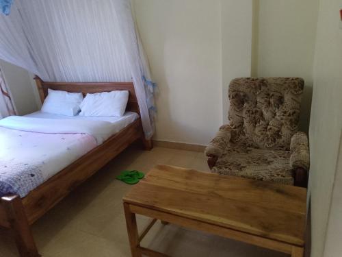 a bedroom with a bed and a chair and a table at VICTORIA RIDGE HOTEL ltd in Meru