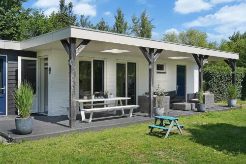 アウウドルプにあるPrinsenhof 65 - Ouddorp NOT INTENDED FOR COMPANY OR WORK-RELATED STAYSの白い家(ピクニックテーブル、ベンチ付)