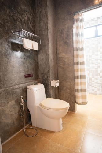 a bathroom with a toilet and a shower curtain at The Proud Hotel in Ubon Ratchathani