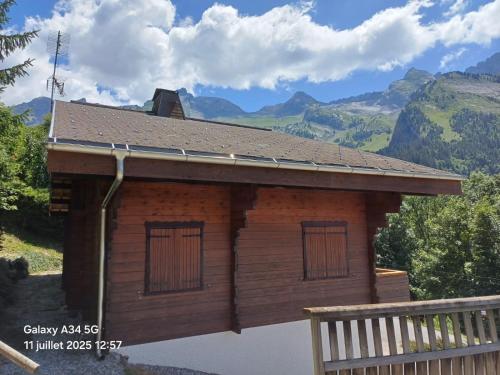 a log cabin with mountains in the background at Chalet aux confins à proximité du télécabine de Balme in La Clusaz