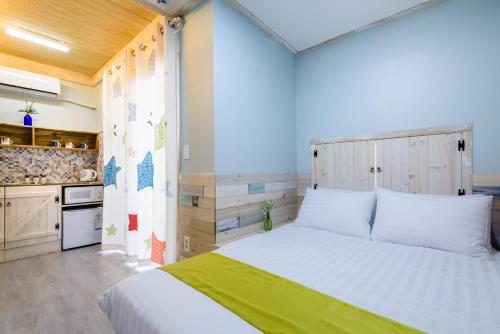 a bedroom with a white bed and a kitchen at White star in Jeju