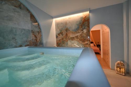 a jacuzzi tub in a room with a stone wall at Mata's Apartments in Tinos Town