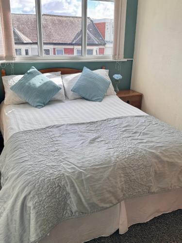 a bed with blue pillows in a room with a window at Kendal Hotel in Blackpool