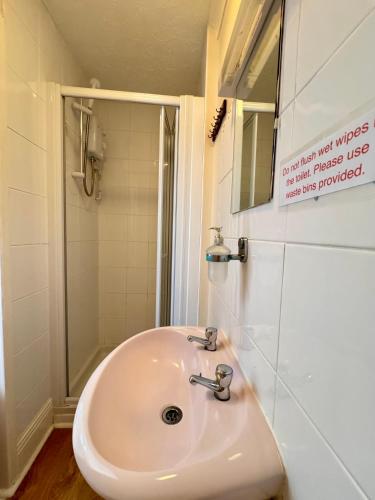 a white sink in a bathroom with a shower at Kendal Hotel in Blackpool