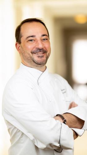 a man in a chefs outfit is smiling at Villa Rosa Kempinski in Nairobi