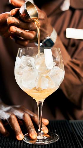 a person is pouring a drink into a glass at Villa Rosa Kempinski in Nairobi