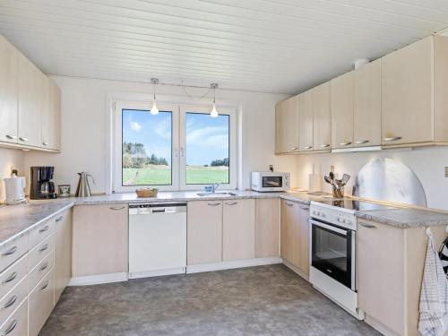 a kitchen with white cabinets and a large window at Holiday Home Kerrin - 1km from the sea by Interhome in Hanstholm