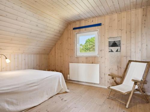 a bedroom with a bed and a window and a chair at Holiday Home Eikka - 100m from the sea by Interhome in Knebel