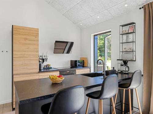 a kitchen with a black counter top and chairs at Holiday Home Syni - 450m from the sea by Interhome in Sæby